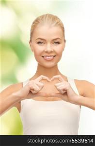 love and gesture concept - smiling woman showing heart shape gesture