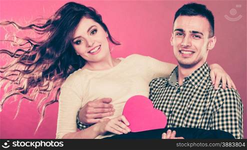 Love and happiness concept. Couple with heart shaped box. Handsome man holding cheerful woman on hands red background