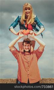 Love and happiness concept. Woman and man young hipster couple in love playing sharing free time having fun holding red heart, outdoor against sky