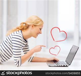 love and internet concept - smiling student girl pointing her finger at laptop screen in college