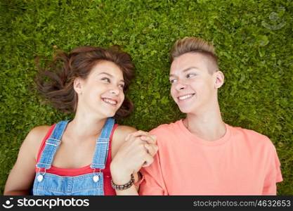 love and people concept - happy teenage couple lying on grass at summer. happy teenage couple lying on grass at summer