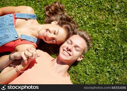 love and people concept - happy teenage couple lying on grass at summer. happy teenage couple lying on grass at summer