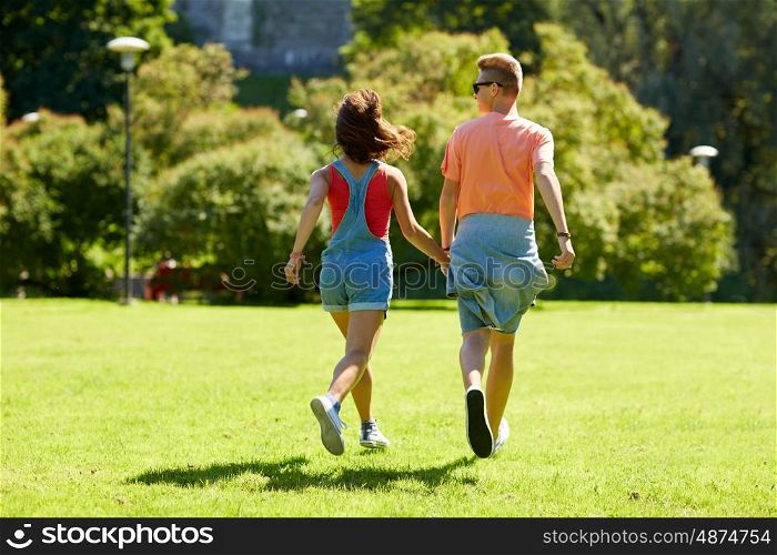 love and people concept - happy teenage couple walking and looking at each other in summer park. happy teenage couple walking at summer park