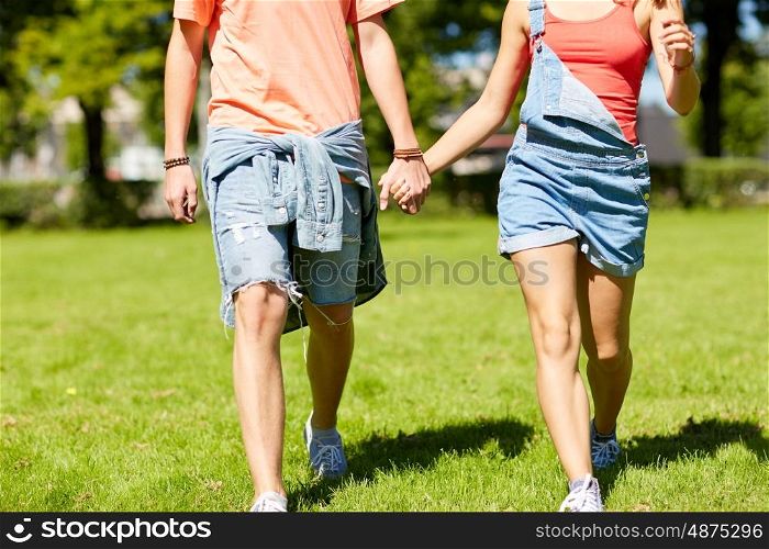 love and people concept - happy teenage couple walking and looking at each other in summer park. happy teenage couple walking at summer park