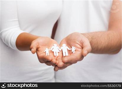 love and relationships concept - closeup of couple cupped hands showing paper man family