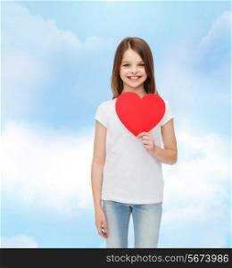 love, charity, childhood and people concept - beautiful little girl sitting at table and holding red heart cutout over cloudy sky background