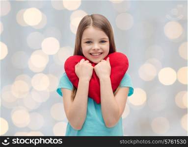love, charity, holidays, children and people concept - smiling little girl with red heart over lights background