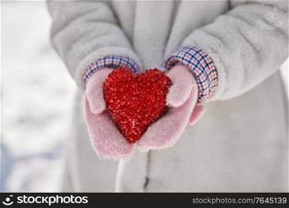 love, christmas and valentine&rsquo;s day concept - close up of little girl holding heart in winter. close up of little girl holding heart in winter