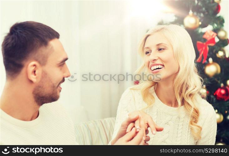 love, christmas, couple, proposal and people concept - happy man giving diamond engagement ring to woman at home. man giving woman engagement ring for christmas