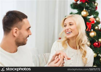 love, christmas, couple, proposal and people concept - happy man giving diamond engagement ring to woman at home