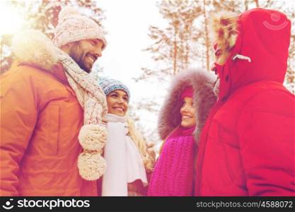 love, christmas, season, friendship and people concept - group of smiling men and women talking in winter forest. group of smiling men and women in winter forest