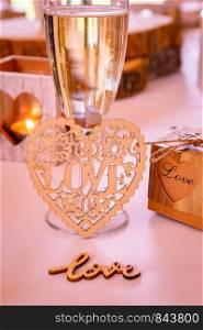 Love concept. Champagne glass with love text and heart shapes on accessories in a wedding setting