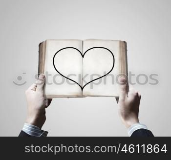 Love concept. Close up of male hands holding opened book