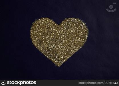love concept image of heart shape made of golden glitter on blue paper texture background