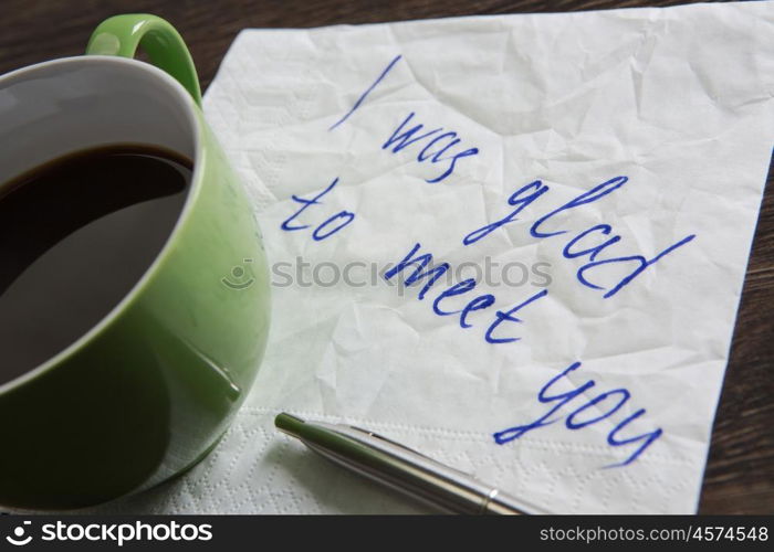 Love confession on napkin. Romantic message written on napkin and cup of coffee on wooden table