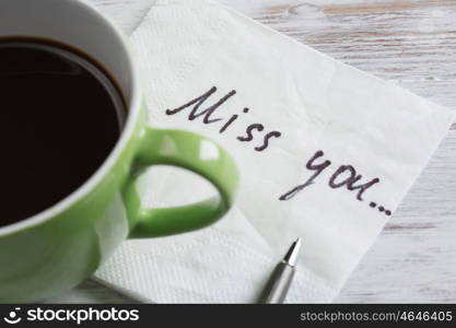 Love confession on napkin. Romantic message written on napkin and cup of coffee on wooden table