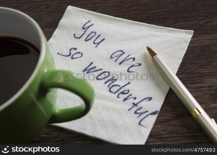 Love confession on napkin. Romantic message written on napkin and cup of coffee on wooden table