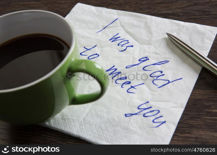 Love confession on napkin. Romantic message written on napkin and cup of coffee on wooden table