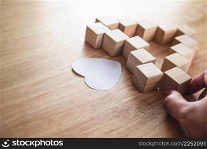 Love connection concept. Someone assembles wood blocks to be heart shape.