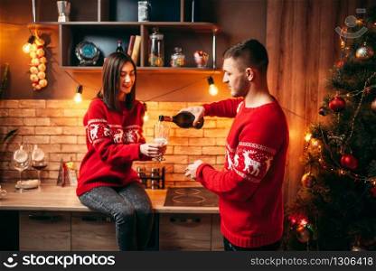Love couple, a man pours champagne in a woman&rsquo;s glass, romantic christmas celebration. Man and woman celebrate xmas together
