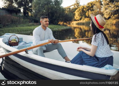 Love couple boating on lake at summer day. Romantic meeting, boat ride, man and woman walking along the river. Love couple boating on lake, romantic meeting