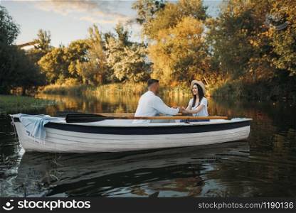Love couple boating on lake at summer day. Romantic meeting, boat ride, man and woman walking along the river. Love couple boating on lake, romantic meeting