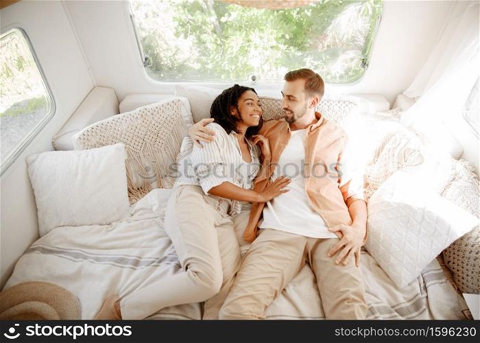 Love couple embraces in rv bed, camping in a trailer. Man and woman travels on van, romantic vacations on motorhome, campers leisures in camping car. Love couple embraces in rv bed, camping in trailer