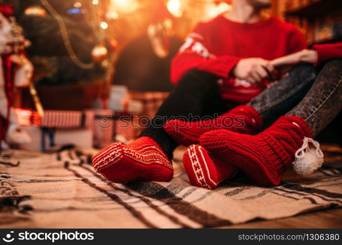 Love couple happy together, christmas holidays. Xmas celebration, man and woman sitting on the floor, boxes with gifts on background