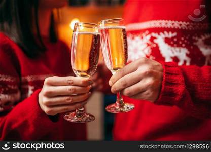 Love couple holds glasses with champagne, romantic christmas celebration. Man and woman celebrate xmas together. Couple holds glasses with champagne, christmas