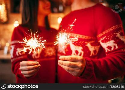 Love couple holds sparklers in hands, christmas romantic celebration. Man and woman celebrate xmas together