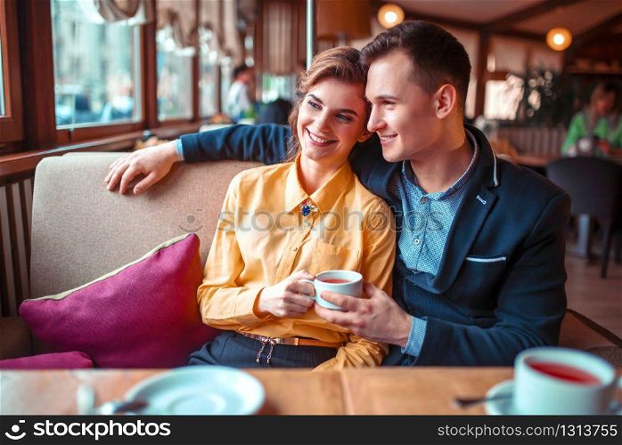 Love couple hugs and looking at the window in restaurant. Man and woman beautiful relationship