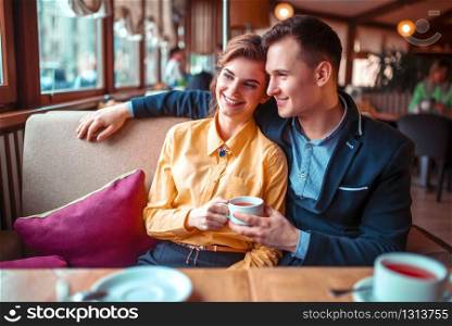 Love couple hugs and looking at the window in restaurant. Man and woman beautiful relationship