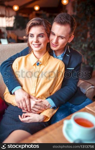 Love couple hugs and looking at the window in restaurant. Man and woman beautiful relationship. Love couple hugs and looking at the window