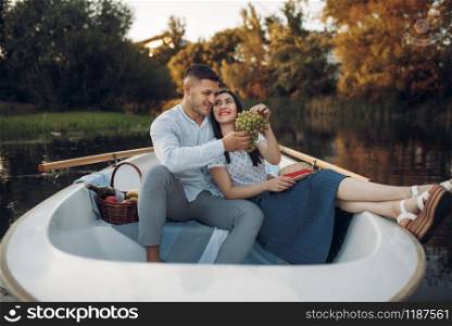 Love couple hugs in a boat on quiet lake at summer day. Romantic meeting, boating trip, man and woman walking along the river. Love couple hugs in a boat on quiet lake