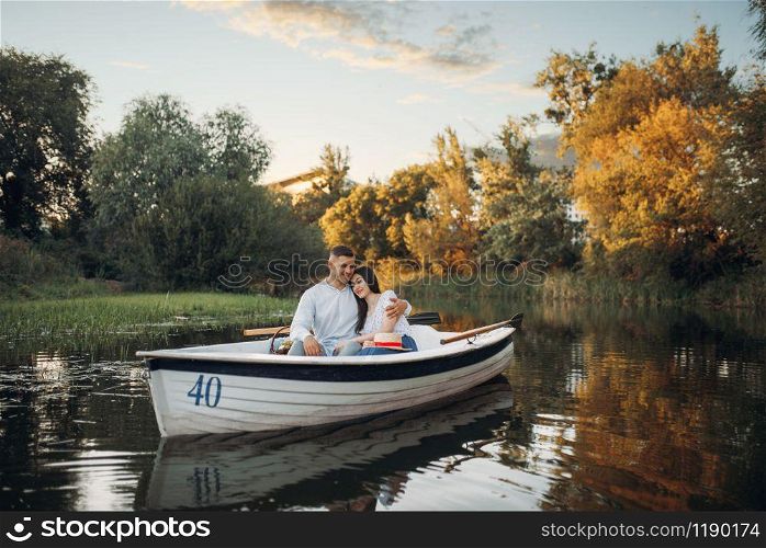 Love couple hugs in a boat on quiet lake at summer day. Romantic meeting, boating trip, man and woman walking along the river. Love couple hugs in a boat on quiet lake