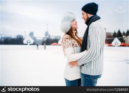 Love couple hugs on skate rink. Winter skating on open air, active leisure, ice-skating, man and woman happy together