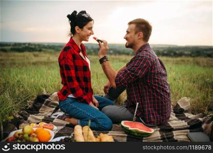 Love couple hugs, picnic in summer field. Romantic junket, man and woman leisure together, happy family weekend. Love couple hugs, picnic in summer field