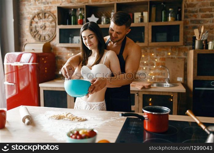 Love couple in underwear cooking on the kitchen, romantic morning. Naked man and woman preparing breakfast at home, food preparation without clothes