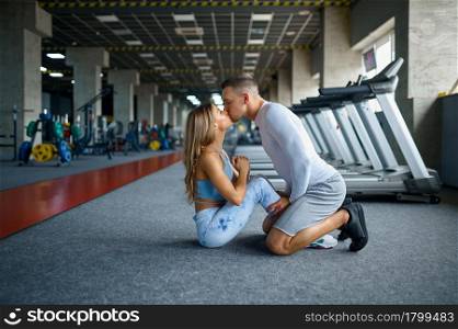 Love couple kissing, fitness training in gym. Athletic man and woman on workout in sport club, active healthy lifestyle, physical wellness. Love couple kissing, fitness training in gym