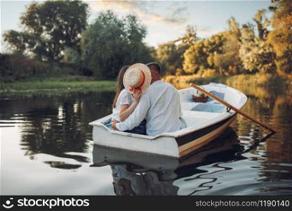 Love couple kissing in boat on lake at summer day. Romantic date, boating trip, man and woman walking along the river. Love couple kissing in boat on lake