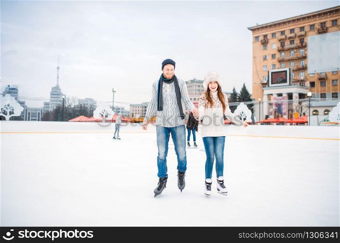 Love couple learn to skate on the rink. Winter skating on open air, active leisure, ice-skating. Love couple learn to skate on the rink