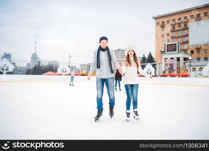 Love couple learn to skate on the rink. Winter skating on open air, active leisure, ice-skating. Love couple learn to skate on the rink