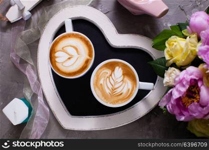 Love couple of cappuccino. Latte art in two cups of cappuccino on the heart shape tray. Happy morning Valentine day couple