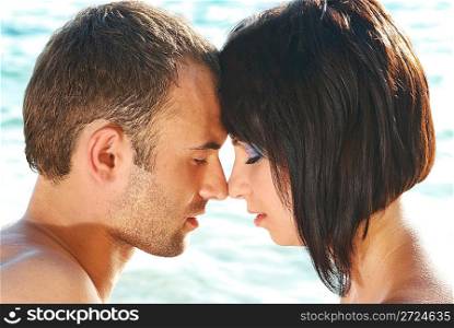 Love couple on the beach against water backdround