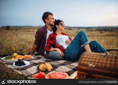 Love couple, picnic on plaid in summer field. Romantic junket of man and woman. Love couple, picnic on plaid in summer field