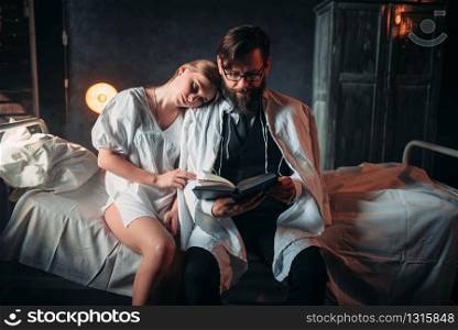 Love couple reading a book in hospital room. Illness of female patient in clinic, health recovery and treatment. Love couple reading a book in hospital room