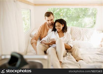 Love couple relax in bed, camping in a trailer. Man and woman travels on van, romantic vacations on motorhome, campers leisures in camping-car. Love couple relax in bed, camping in a trailer