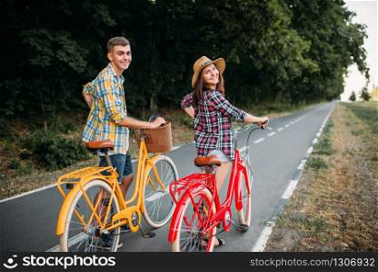 Love couple walk on vintage bikes, romantic journey of young man and woman. Boyfriend and girlfriend together outdoor, retro bicycle. Love couple walk on vintage bikes romantic journey