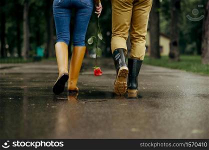 Love couple walks in park, summer rainy day. Man and woman leisures together, romantic date on walking path, wet weather in alley. Love couple walks in park, summer rainy day