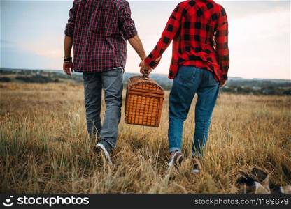 Love couple with basket, picnic in summer field. Romantic junket, man and woman leisure together, happy family weekend